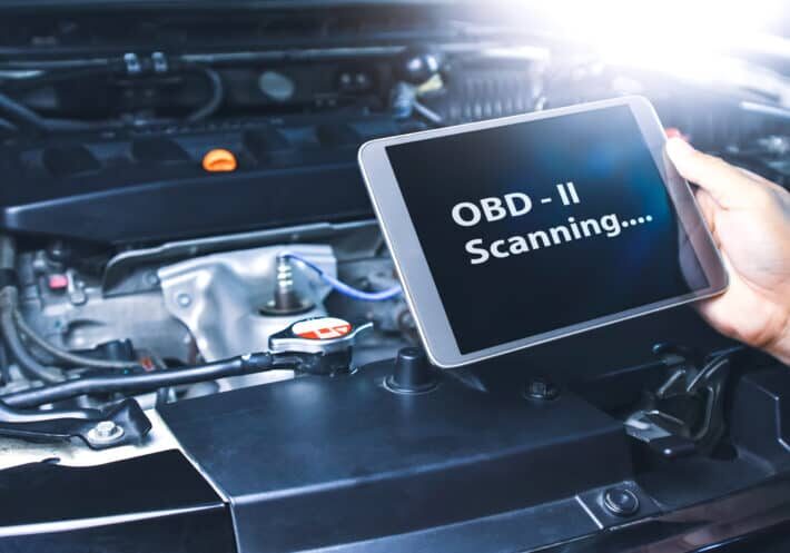 Technician diagnostics of code failure with OBD2 scanner technology on tablet in the auto repair garage